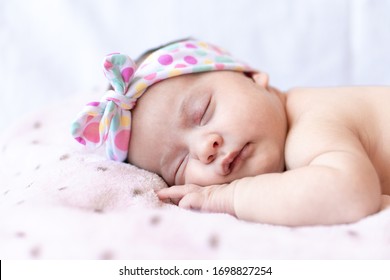 Adorable Baby Newborn With A Headband Sleeping On Stomach