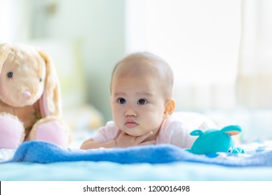 Adorable Baby On Bedroom On Morning. Newborn 5 Months Child Relaxing In Bed. New Born Kid During Tummy Time With Stuffed Animal Toys.