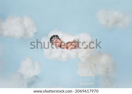 Adorable baby sleeping on clouds in blue sky like little angel.