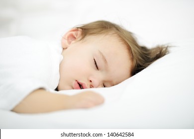 Adorable baby sleeping on white bed with copy space