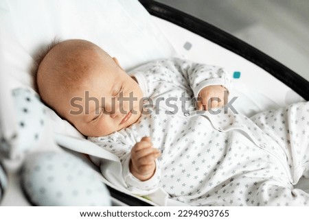 Adorable baby sleeps in baby rocker in room. Newborn concept. Close up