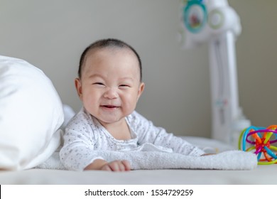Adorable baby smiling boy doing tummy time on bed. Family morning at home. Baby looking at the camera.