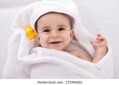 Adorable Baby Smiling Wrapped In White Towel With Yellow Duck, Isolated On White