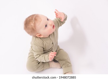 Adorable baby surprised by something and playing on the white floor