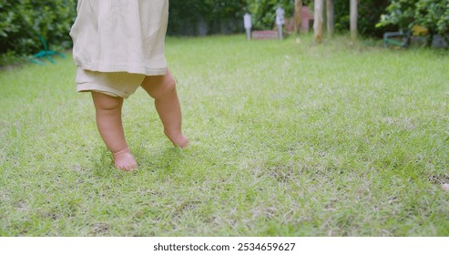 Adorable Baby Taking First Steps on Lush Green Grass in a Sunny Garden, Capturing the Joy and Innocence of Childhood Exploration and Growth in a Natural Outdoor Setting - Powered by Shutterstock