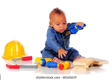 An adorable biracial baby in workman overalls eagerly playing with plastic tools.  isolated on white.