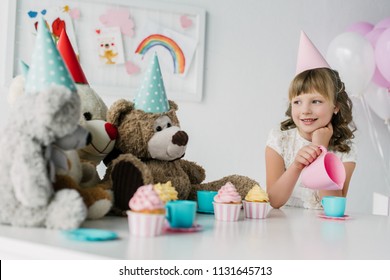 adorable birthday child having tea party with teddy bears in cones at table with cupcakes  - Powered by Shutterstock