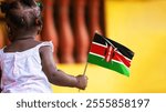 Adorable black African kid female baby todler girl standing holding Kenya national flag in hand. December 12 Independence Day celebration. back view
