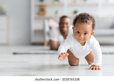Adorable Black Infant Baby Crawling Away From Father While Resting Together In Living Room At Home, Cute Little African American Toddler Child Playing With Daddy, Selective Focus, Copy Space - Shutterstock ID 2018765108
