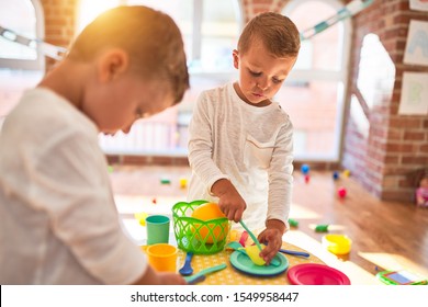 Adorable blonde twins playing around lots of toys. Cooking plastic food toy at kindergarten - Shutterstock ID 1549958447