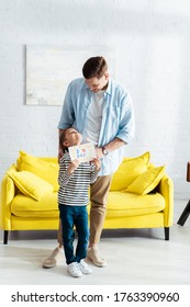 Adorable Boy Looking At Father While Holding Handmade Fathers Day Greeting Card With Lettering And Heart Symbol