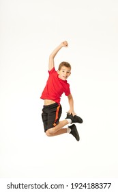 Adorable Boy Raising Arm And Jumping In Studio