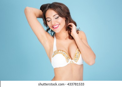 Adorable brunette in bikini posing isolated on the blue background