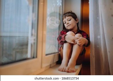 Adorable Caucasian 6 Years Old Boy In Red Flannel Plaid Shirt And Shorts Sitting On Window Sill And  Dreaming To Go Outside. Staying Home Because Cold And Flu. Image With Selective Focus