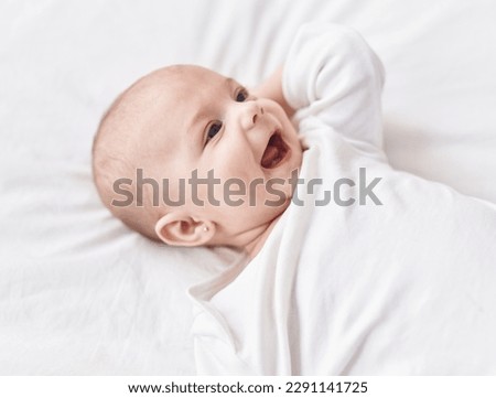 Adorable caucasian baby lying on bed smiling at bedroom