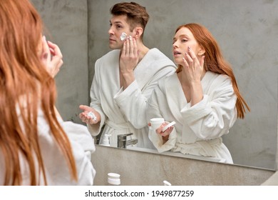 Adorable Caucasian Couple Take Care Of Facial Skin, Woman Applying Cream While Man Is Going To Shave Stubble