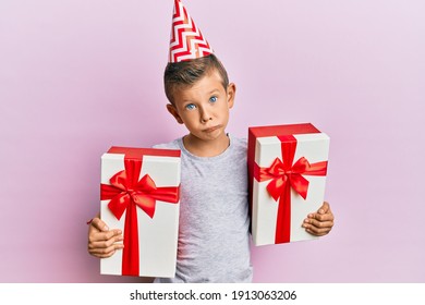 Adorable Caucasian Kid Wearing Birthday Hat Holding Presents Depressed And Worry For Distress, Crying Angry And Afraid. Sad Expression. 