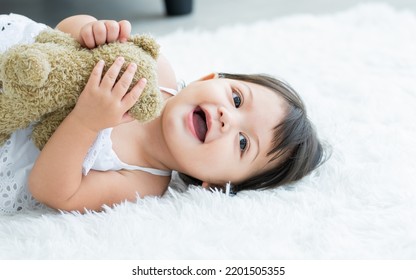 Adorable Caucasian Little Baby Daughter Girl, Laughing, Smiling With Happiness, Good Health, Relax Day Sleeping And Laying Down Alone With Lullaby, Hugging Bear Doll On White Bed At Home. Kid Concept