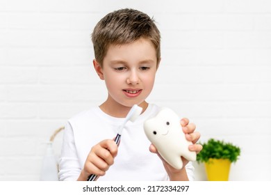 Adorable Child Holding A Toothbrush And A Toy Tooth And Learning To Brush Teeth. Morning Dental Hygiene And Daily Routine For Childrens Health. Caries Protection Of The Oral Cavity And Milk Teeth.