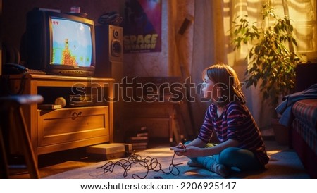 Adorable Child Playing Eight Bit Arcade Video Game on a Console at Home in Her Room with Eighties Interior. Young Girl Reaches End of Level and Wins. Nostalgic Retro Childhood Concept.