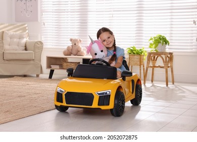 Adorable Child With Toy Driving Car In Room At Home