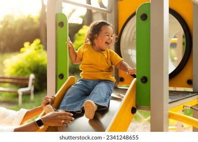 Adorable Chinese Baby Girl Riding Slides At Public Playground In Park, Mommy Catching Her Little Daughter, Having Fun And Playing Together. Toddler Child Enjoying Time At Play Ground With Mom - Powered by Shutterstock