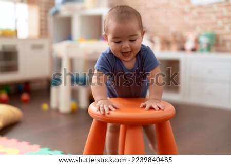 Adorable chinese toddler smiling confident leaning on stool standing at kindergarten