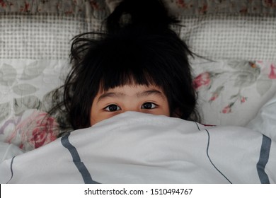 Adorable cute asian little girl peek under a blanket awaked up in her bed - Shutterstock ID 1510494767