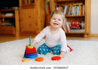 Adorable Cute Beautiful Little Baby Girl Playing With Educational Wooden Toys At Home Or Nursery. Toddler With Colorful Stack Pyramid And Music Toy. Happy Healthy Child Having Fun With Different Toys