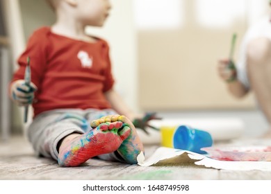 Adorable Cute Caucasian Little Blond Siblings Children Enjoy Having Fun Painting With Brush And Palm At Home Indoors . Cheerful Happy Kids Smiling Drawing Masterpiece Art Picture. Messy Dirty Room