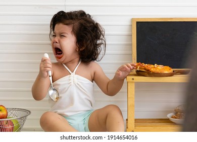 Adorable Cute Hispanic Girl Crying Upset When Finished Eating In The Table. The Baby Cry When They Need Milk And Food. The Child Cried When He Tried To Eat Spicy Pizza. Copy Space