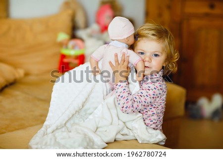 Similar – Baby girl reading book with family in the bed