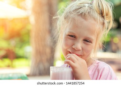 Adorable cute preschooler caucasian blond girl portrait sipping fresh tasty strawberry milkshake coctail at cafe outdoors. Children healthy diet and nutrtion concept - Powered by Shutterstock