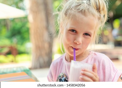 Adorable cute preschooler caucasian blond girl portrait sipping fresh tasty strawberry milkshake coctail at cafe outdoors. Children healthy diet and nutrtion concept - Powered by Shutterstock