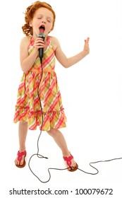 Adorable Elementary Age School Girl Singing Into Microphone Isolated Over White Background.