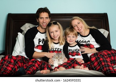 Adorable Family Dressed In Matching Pajamas With Cat For Christmas Holiday Card Photo