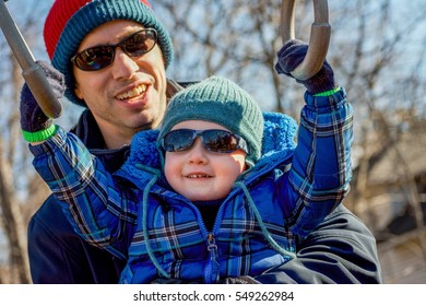 Adorable Father And Son Hanging On Monkey Bars On Playground