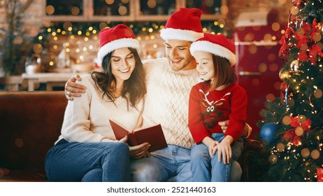 Adorable festive family in red santa hats reading xmas fairy tales together over decorated kitchen, copy space - Powered by Shutterstock