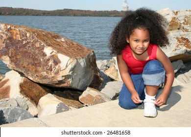 Adorable Five Year Old African American Girl Tying Her Shoe At Park.