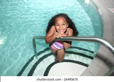 Adorable five year old African American Girl in indoor pool smiling.