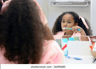 Adorable Five Year Old African American Girl Brushing Teeth In Mirror.