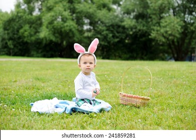 Adorable funny baby boy with bunny ears playing on green grass with Easter eggs - Shutterstock ID 241859281