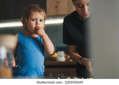 Adorable Funny Blond Little Baby Girl Baking Chocolate Cake And Tasting Dough In Domestic Kitchen. Happy Family. Sweet Food.