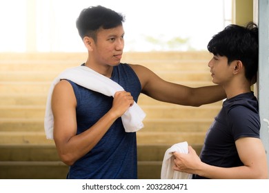 Adorable Gay LGBT Asian Couple Relaxing After A Workout. A Dark-skinned Young Man Leaning In To Talk Closely With His White Friends,  Near The Steps, Sports And Lifestyle. People And Affection LGBT.