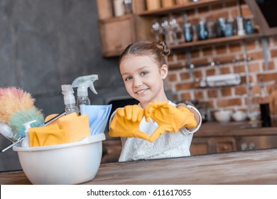 Adorable Girl With Cleaning Supplies Showing Heart Symbol At Home 