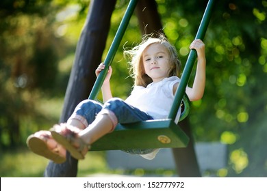 Adorable girl having fun on a swing on summer day - Powered by Shutterstock