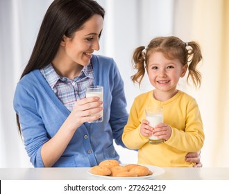 Cô gái đáng yêu đang có một bữa ăn nhẹ lành mạnh với bánh quy và sữa với mẹ.