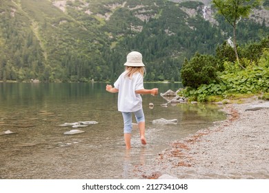 Adorable girl playing by Sea eye (Morskie oko) lake in Poland on warm summer day. Cute child having fun, summer activities for kids.