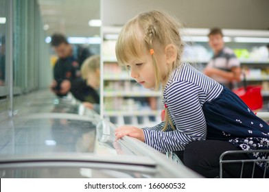 Adorable Girl At Shopping Cart Select Ice Cream In Supermarket