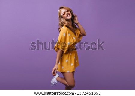 Adorable girl in sparkle glasses  funny dancing on purple background. Indoor photo of graceful caucasian lady with bronze skin.